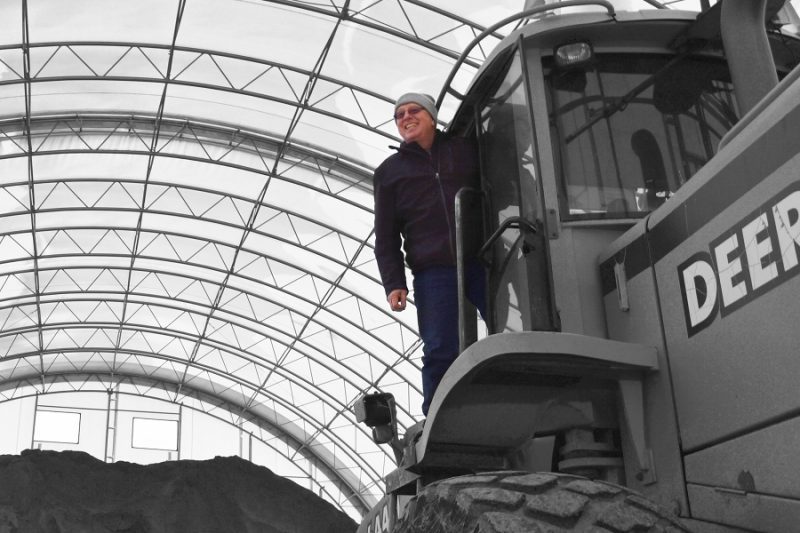 Worker stands atop construction equipment inside a fabric shelter