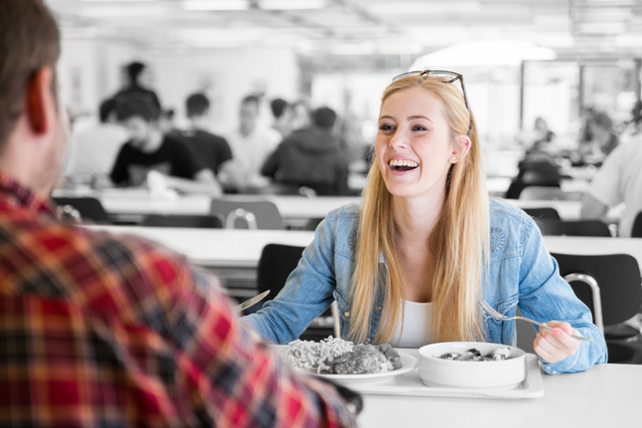 Two people enjoying eating in a cafeteria