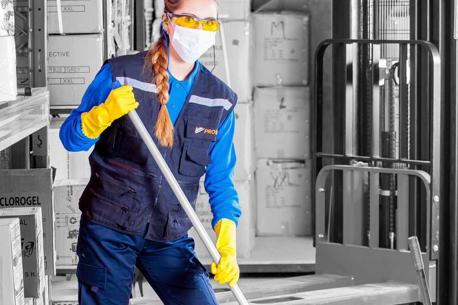 worker using cleaning supplies and wearing PPE