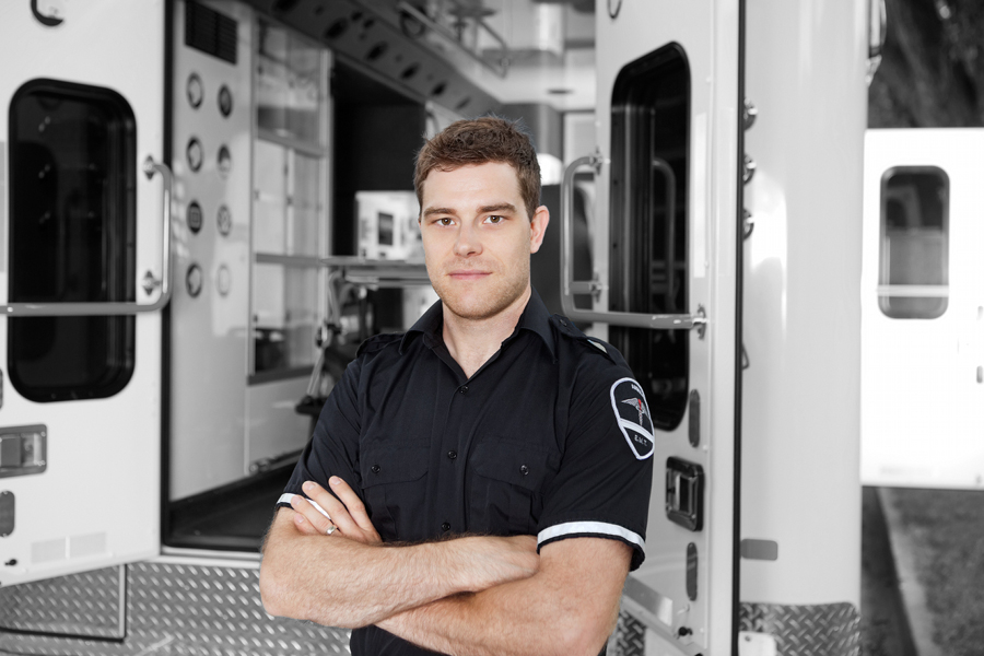 Paramedic in uniform standing in front of an open ambulance