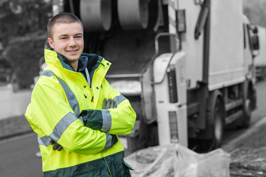 garbage collection worker standing near a garbage truck